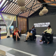 A man and two women sit on chairs. Behind them is a screen with the words "HEALTHTECH HUB AFRICA LAUNCH" in white.